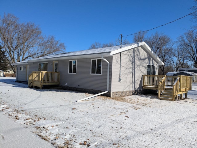 snow covered rear of property with a wooden deck