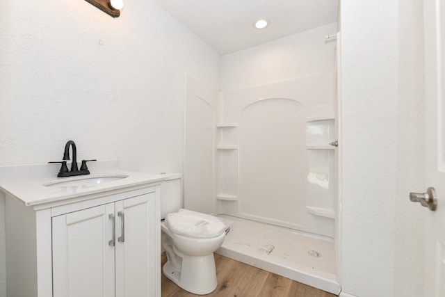 bathroom featuring walk in shower, vanity, toilet, and hardwood / wood-style floors