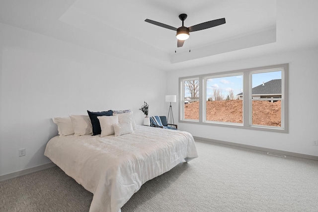 bedroom with ceiling fan, a tray ceiling, carpet flooring, and baseboards