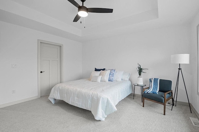 bedroom with a raised ceiling, ceiling fan, and carpet flooring