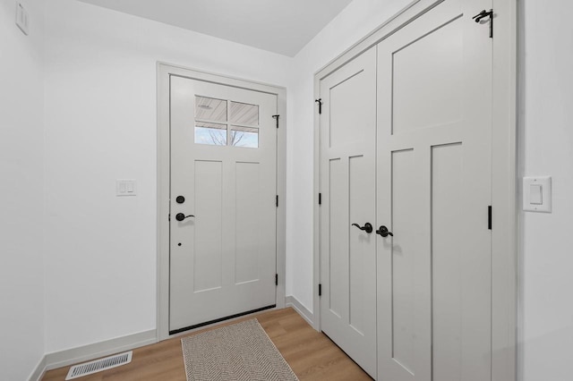 foyer featuring light wood-style floors, baseboards, and visible vents