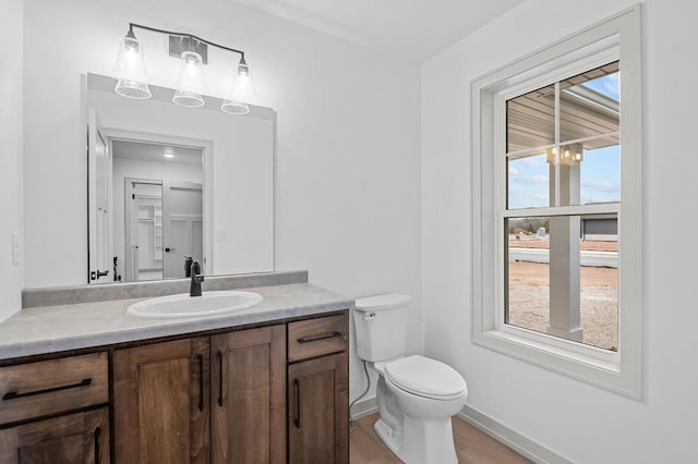 bathroom with baseboards, a notable chandelier, vanity, and toilet