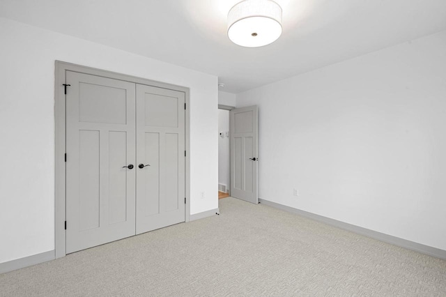 unfurnished bedroom featuring light colored carpet and a closet