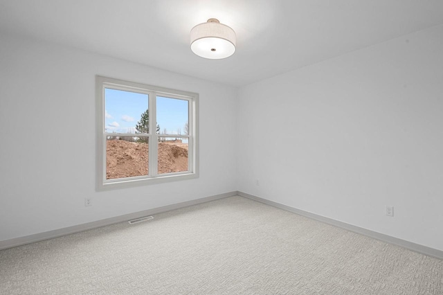 carpeted spare room with visible vents and baseboards