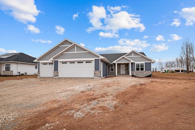 craftsman house with stone siding, an attached garage, and driveway