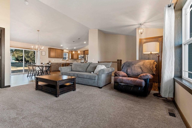 carpeted living room with a chandelier and vaulted ceiling