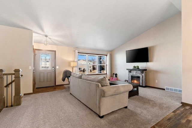 living room featuring lofted ceiling, carpet flooring, and a fireplace