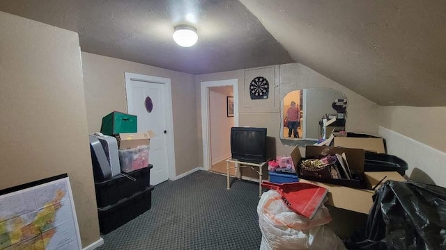 interior space featuring dark colored carpet, lofted ceiling, and a textured ceiling