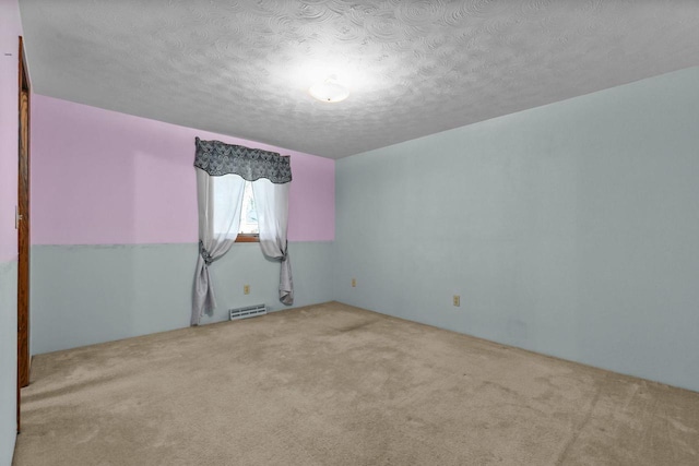 unfurnished room featuring light carpet and a textured ceiling