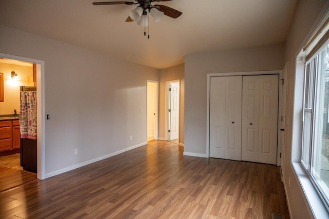 unfurnished bedroom featuring dark hardwood / wood-style flooring, ensuite bath, a closet, and ceiling fan