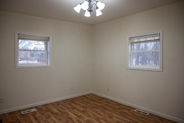 unfurnished room with a chandelier and dark hardwood / wood-style flooring