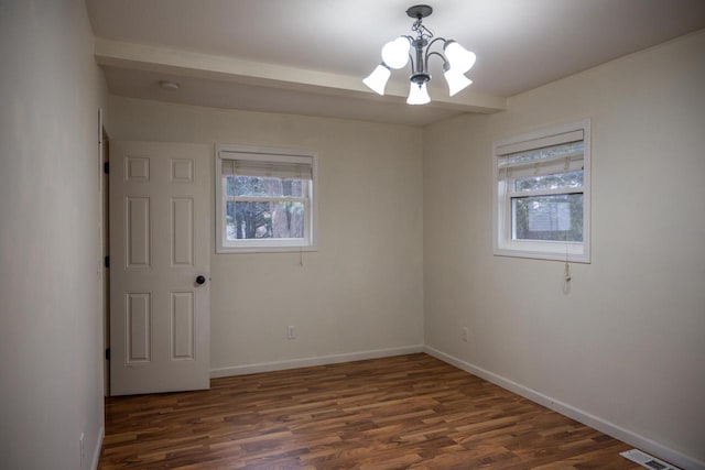 empty room with plenty of natural light, dark wood-type flooring, and an inviting chandelier