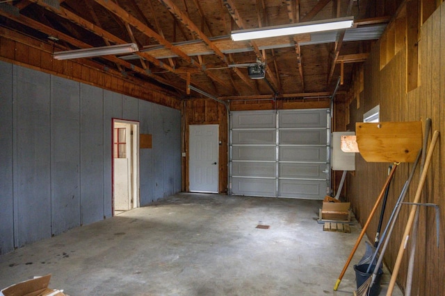 garage featuring a garage door opener and wooden walls