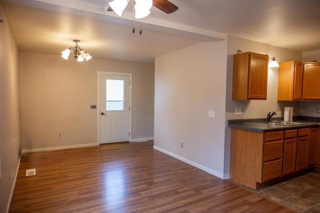 kitchen with ceiling fan with notable chandelier, sink, and dark wood-type flooring