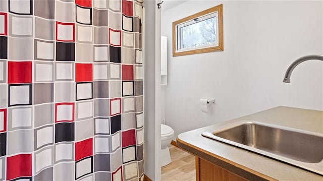 bathroom with sink, a shower with curtain, wood-type flooring, and toilet