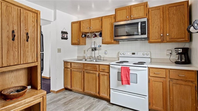 kitchen with electric stove, sink, backsplash, and light hardwood / wood-style flooring