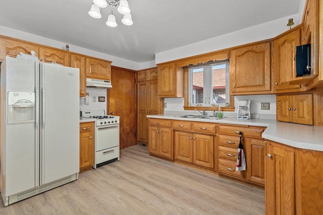 kitchen with an inviting chandelier, white appliances, sink, and light hardwood / wood-style flooring