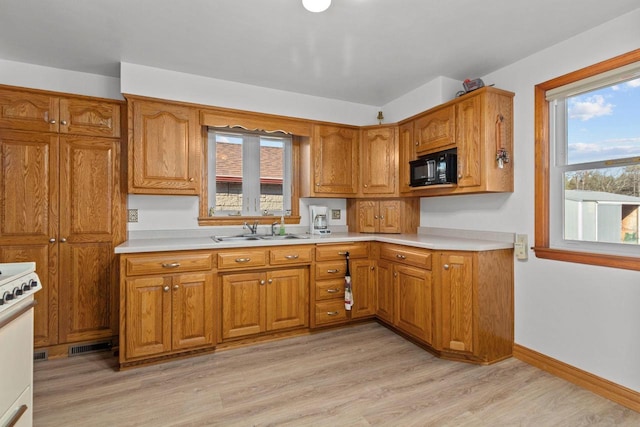 kitchen with white range oven, sink, and light wood-type flooring