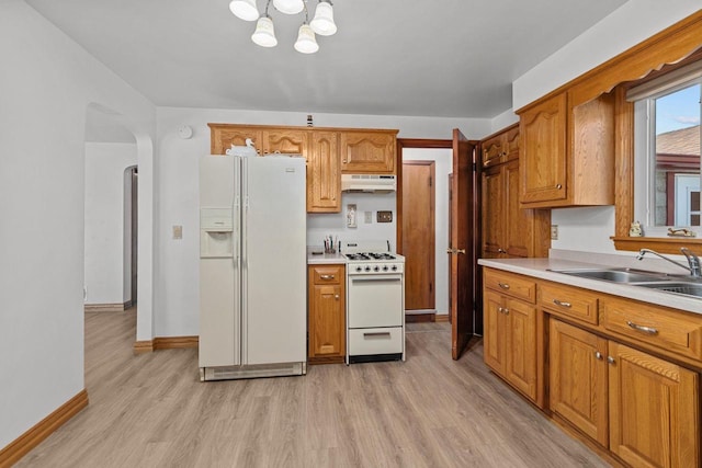 kitchen with an inviting chandelier, sink, white appliances, and light hardwood / wood-style flooring