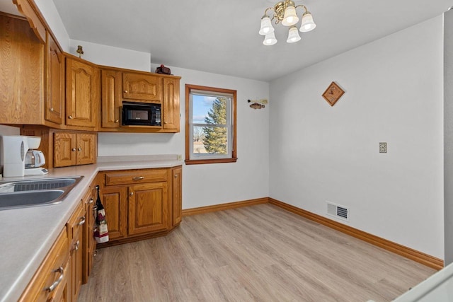 kitchen with sink, light hardwood / wood-style flooring, black microwave, and a chandelier