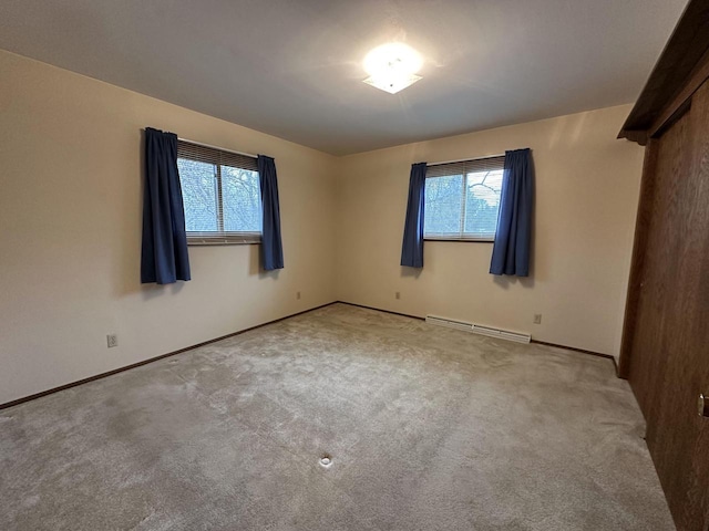 unfurnished room featuring light carpet and a baseboard heating unit