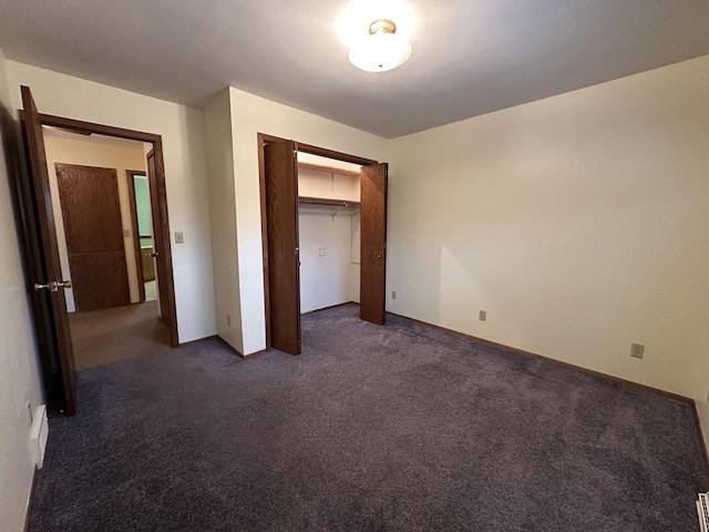 unfurnished bedroom featuring a closet and dark colored carpet