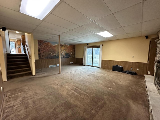 basement with a paneled ceiling and wooden walls