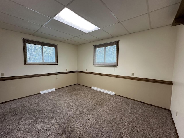 unfurnished room featuring carpet and a drop ceiling