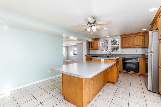 kitchen featuring light tile patterned floors, a kitchen breakfast bar, oven, and a kitchen island