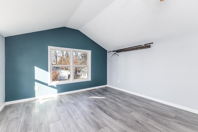 spare room featuring vaulted ceiling and light hardwood / wood-style floors