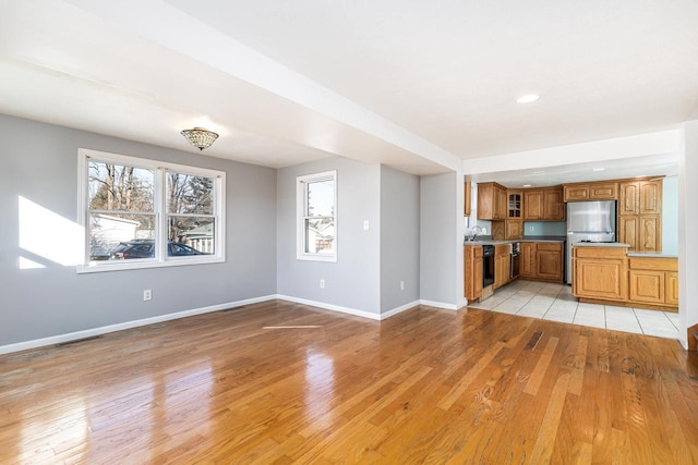 kitchen featuring stainless steel fridge, dishwasher, sink, and light wood-type flooring