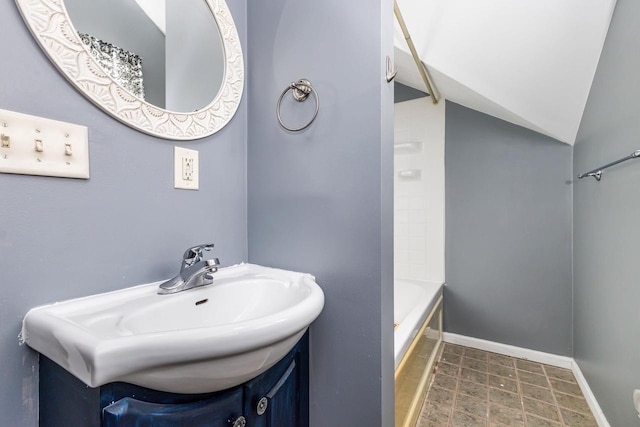 bathroom with vanity, lofted ceiling, and a washtub