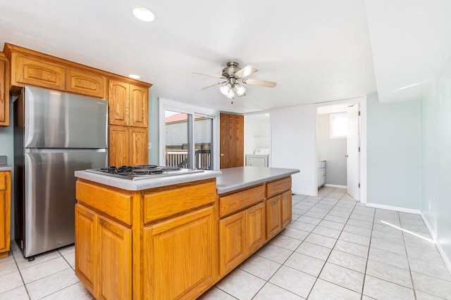 kitchen featuring separate washer and dryer, a center island, light tile patterned floors, appliances with stainless steel finishes, and ceiling fan