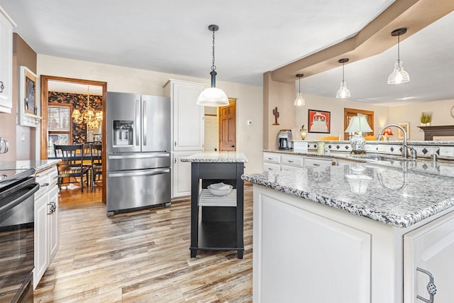 kitchen featuring light stone countertops, stainless steel fridge with ice dispenser, a kitchen island, and white cabinets