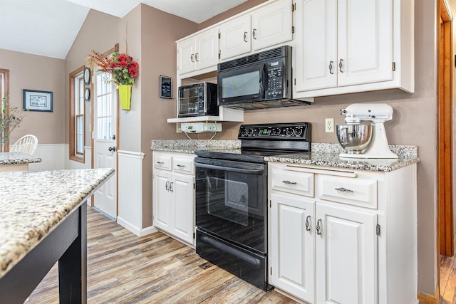 kitchen featuring white cabinetry, light stone countertops, black appliances, and light hardwood / wood-style floors