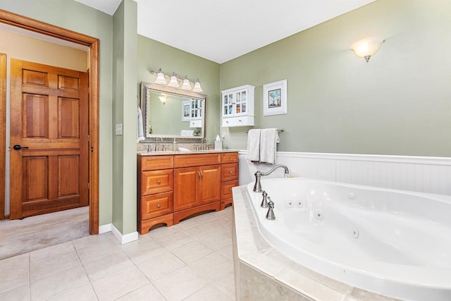 bathroom featuring tile patterned flooring, vanity, and tiled bath