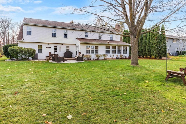 back of house with an outdoor living space, a patio, and a lawn