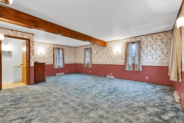 carpeted empty room with beamed ceiling