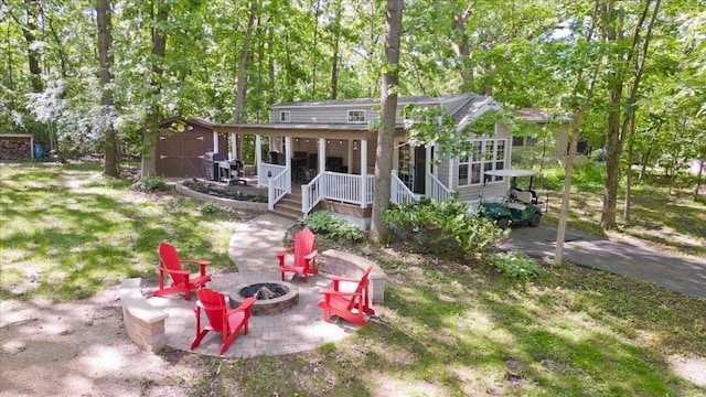 rear view of property featuring a storage unit, a patio, covered porch, and a fire pit