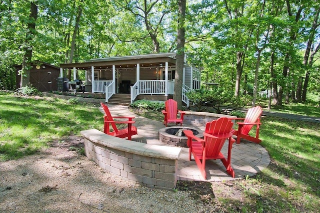 view of patio / terrace featuring a storage shed, a fire pit, and a porch