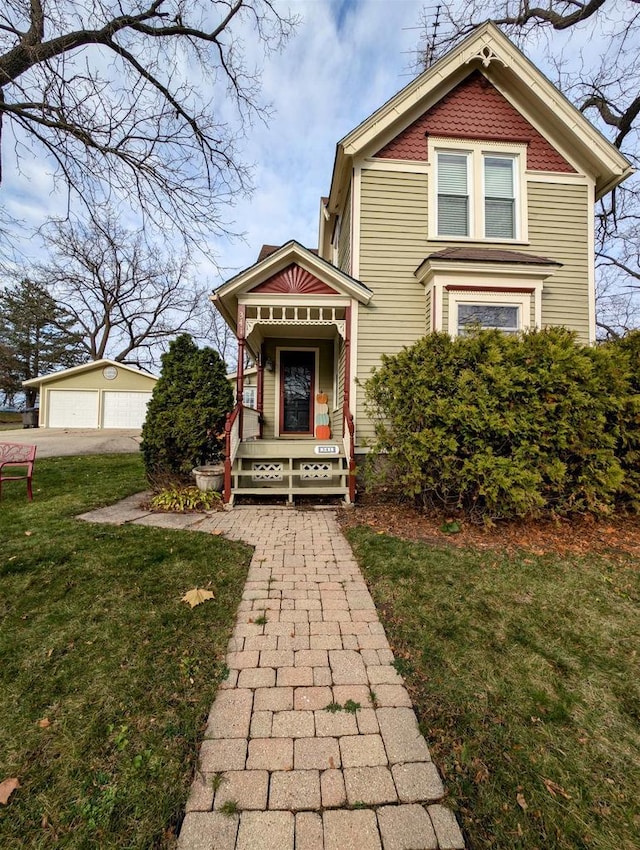 victorian house featuring a garage, an outbuilding, and a front lawn