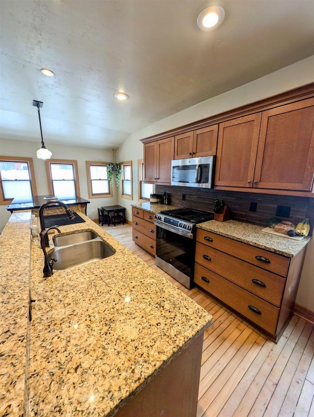 kitchen featuring hanging light fixtures, appliances with stainless steel finishes, sink, and light wood-type flooring