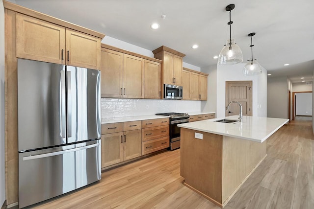 kitchen featuring pendant lighting, sink, appliances with stainless steel finishes, a kitchen island with sink, and light brown cabinets