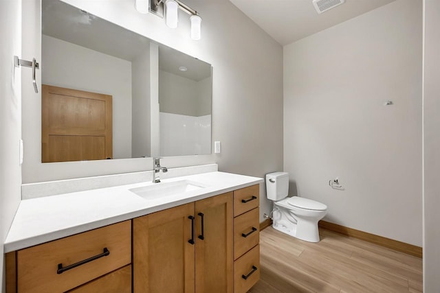 bathroom featuring hardwood / wood-style flooring, vanity, walk in shower, and toilet