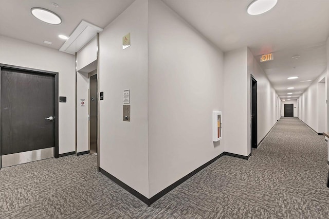 hall with dark carpet and elevator