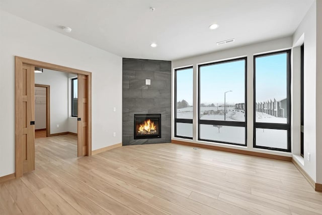 unfurnished living room featuring a fireplace and light hardwood / wood-style floors