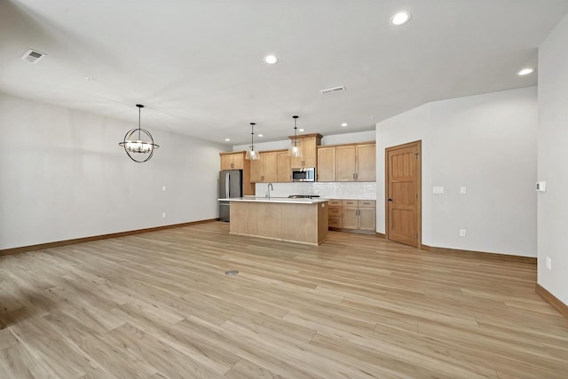 kitchen featuring stainless steel appliances, a kitchen island, light hardwood / wood-style floors, and hanging light fixtures