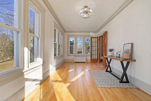 entryway with an inviting chandelier, radiator, crown molding, and light hardwood / wood-style floors