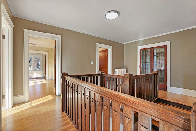 corridor with ornamental molding, radiator, and light hardwood / wood-style flooring