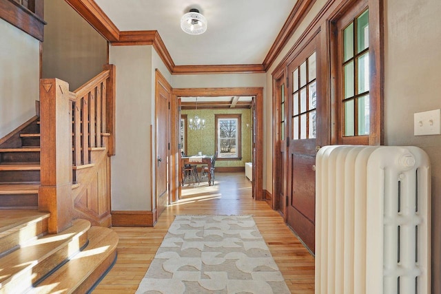 foyer with crown molding, radiator heating unit, and light hardwood / wood-style flooring